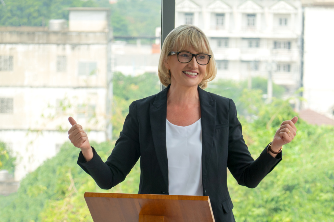 Female Speaker on a Wooden Podium doing a Public Speaking